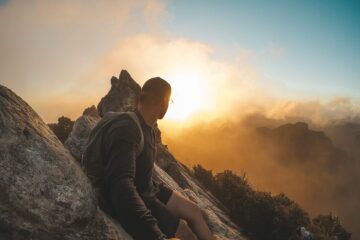 man wearing black long sleeved shirt standing on mountain